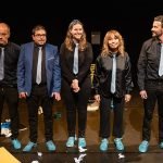 Cinq participants à des cours de théâtre parisiens posent sur scène, illustrant la diversité des talents