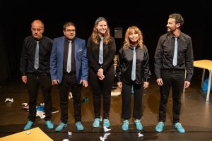 Cinq participants à des cours de théâtre parisiens posent sur scène, illustrant la diversité des talents
