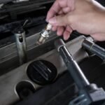 Mécanicien inspectant une bougie d'allumage pour écarter d'autres pannes avant de confirmer les signes d’un démarreur défectueux