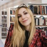 Portrait de l'autrice Céline Estelle souriante dans une bibliothèque pour son livre l’été Gigi.