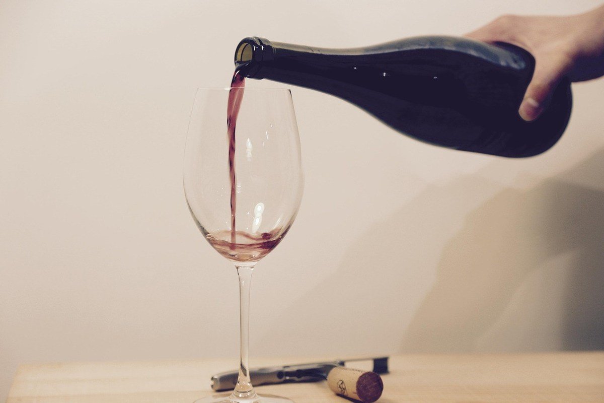 Verre de vin rouge en train d'être rempli par une bouteille tenue au-dessus Verre de vin rouge en train d'être rempli par une bouteille tenue au-dessus