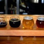 Quatre verres de bière de différentes couleurs sur un support en bois