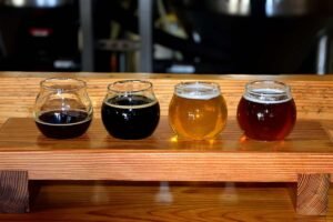 Quatre verres de bière de différentes couleurs sur un support en bois