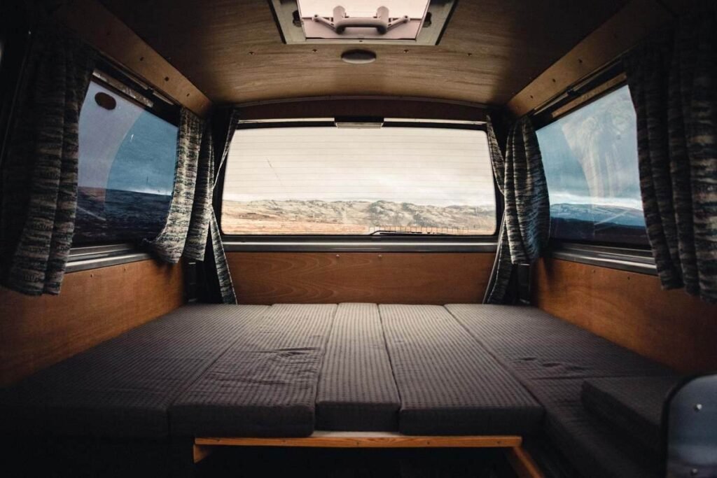 Intérieur d'un véhicule camper avec lit pliant, rideaux et vue extérieure