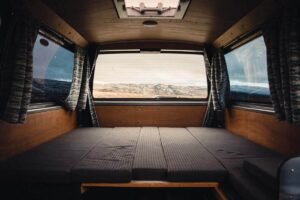 Intérieur d'un véhicule camper avec lit pliant, rideaux et vue extérieure