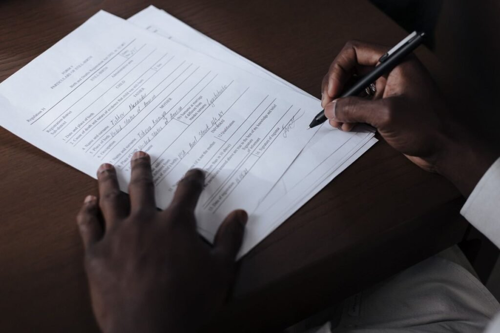 Mains noires écrivant sur un papier avec un stylo sur une table