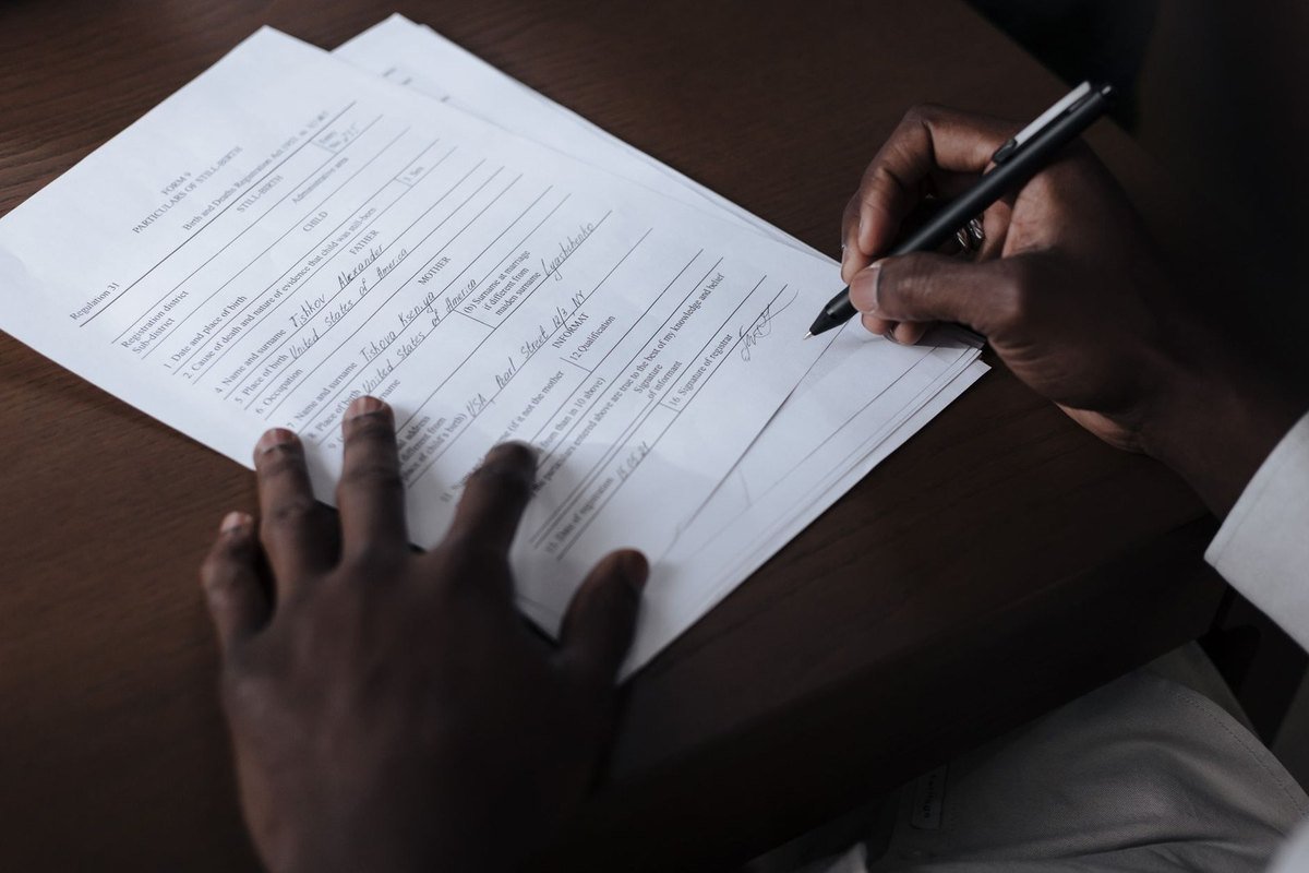 Mains noires écrivant sur un papier avec un stylo sur une table