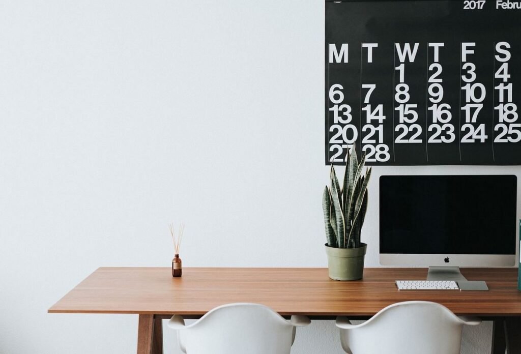 Bureau avec écran Apple, chaises blanches, cactus, calendrier février 2017