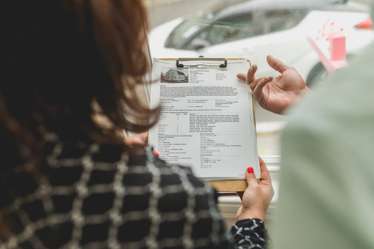 Femme examinant attentivement un document sur un plateau, main d'une autre personne proche