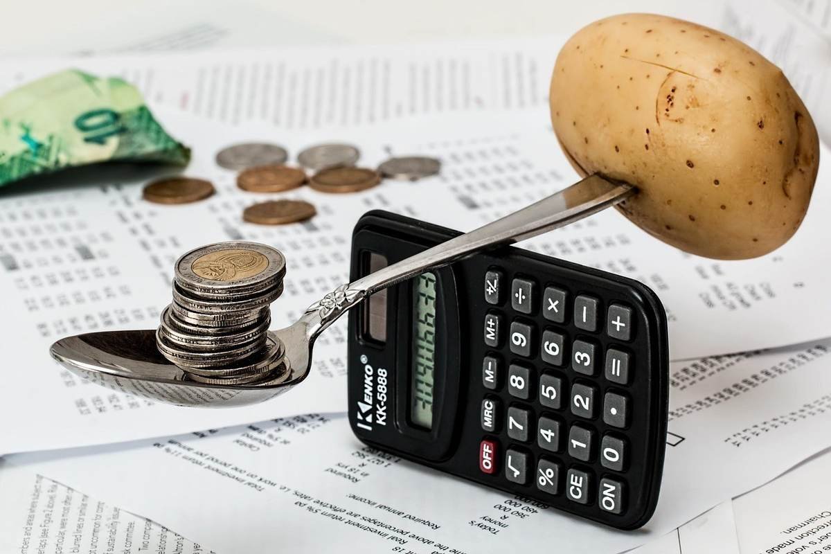 Une cuillère avec des pièces et une pomme de terre sur une calculatrice
